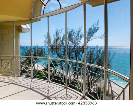 A view of the ocean through an glass window arch of a balcony.