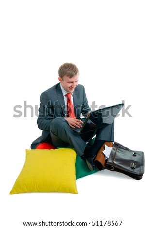 The man the businessman has settled down on pillows behind the working computer