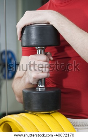 Strong man with dumbbells, focus on hand and dumbbell