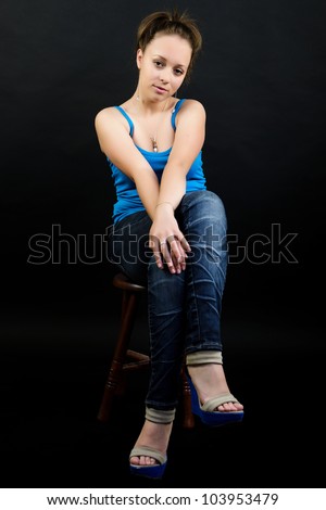 Attractive young woman on chair on dark background