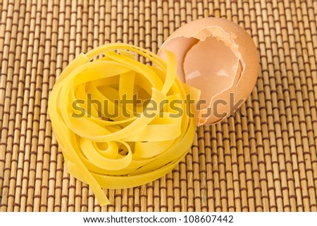 Pasta and empty eggshell on straw background