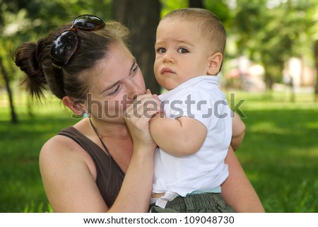 Mother kissing her son\'s hand in the park