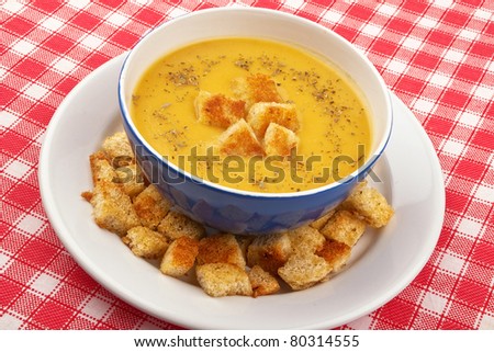Bowl of vegetables cream soup and toast in red and white table cloth