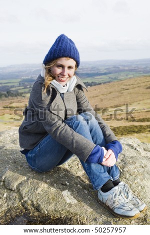 Happy Woman Sat Down Having Reached The Top Of A Mountain