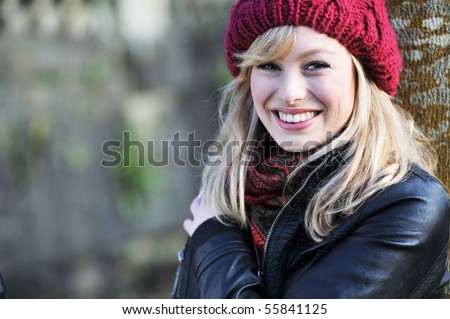 Close up portrait of young caucasian woman outdoors, leaning against a tree