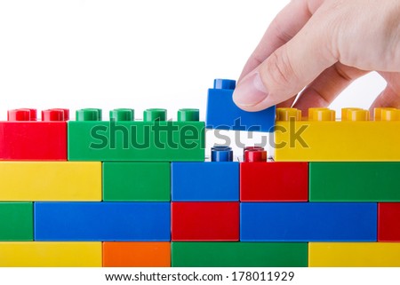 hand building up a wall by stacking up block
