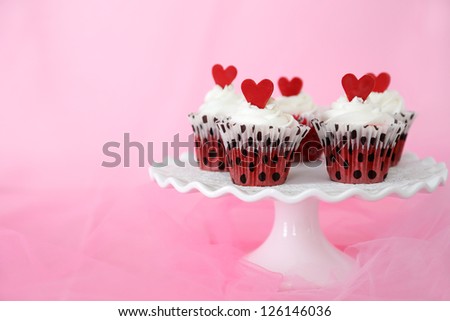 Red velvet cupcakes with cream cheese frosting decorated with red chocolate hearts. Copy space on the side.