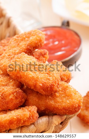 A few nuggets on a plate with ketchup closeup on background
