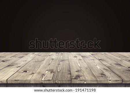 Empty wooden table for product placement or montage with focus to the table top in the foreground, with dark background.