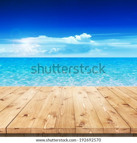 Empty wooden table in a sun drenched summer garden for product placement or montage with focus to the table top in the foreground, with white background.