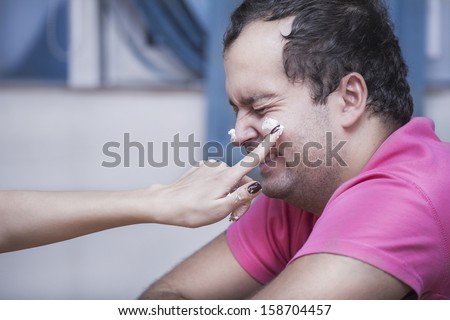 girl\'s hand rubs cake on a guy\'s face