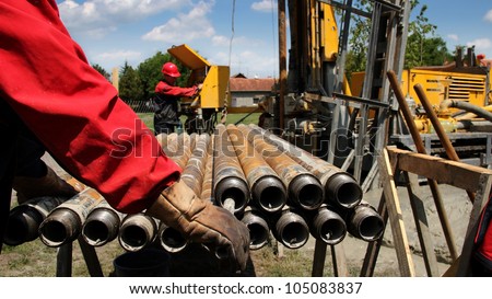 Oil drilling rig workers lifting drill pipe.  Oil and Gas Industry. Drilling Rig. \
Oil and Gas Worker.