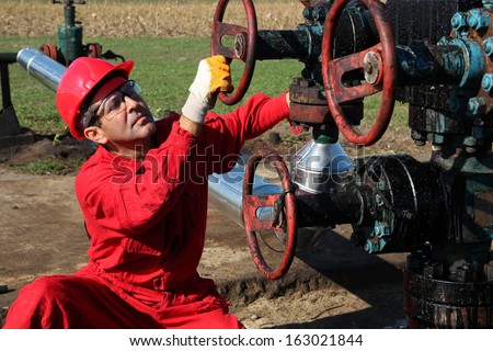 Oil Rig Worker. Oil and gas industry.  Oil worker turning valve on oil rig.