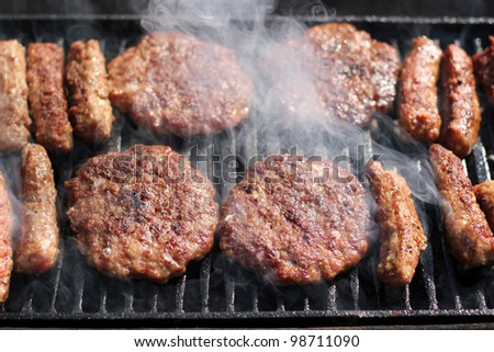 Tasty meat roasted on a grill. Delicious Hamburgers and kebabs on the grill. Barbecue party. Delicious meat on bbq grill. Summer barbecue with mixed meat.