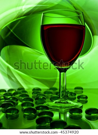 Single wine glass filled with red wine with a green background