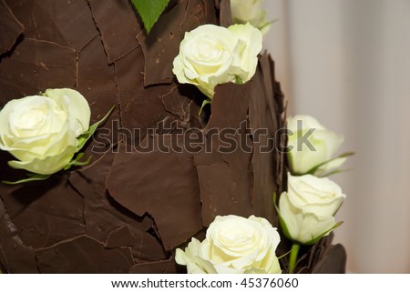 Brown chocolate wedding cake decorated with light yellow roses