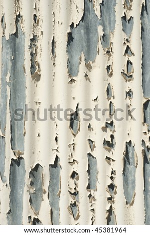 Peeling white paint from curved metal surface on the side of a building