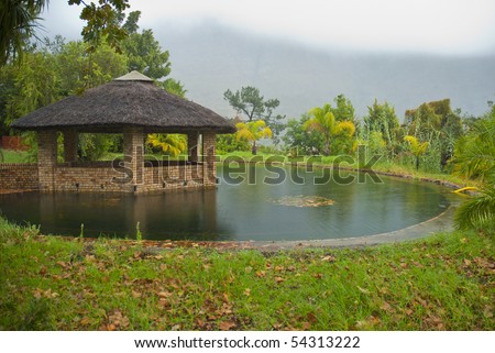Grass Roofed, Brick Gazebo, Surrounded By A Pond And Grass, With ...