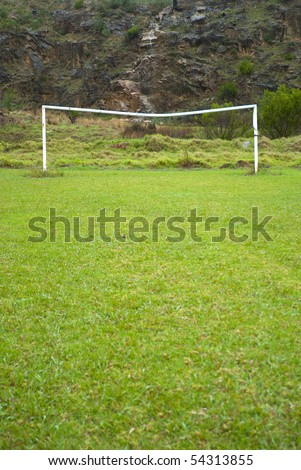 Rural soccer field with white goal posts and a hill behind it