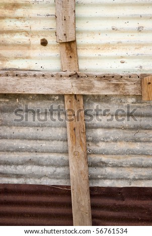 Wooden beams forming a cross on the rusted metal wall of a shack in a township in South Africa