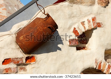 Piece of old wall with rusty milk can in it can be used as background