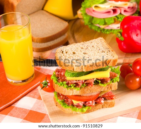 big sandwich with fresh vegetables on wooden board on table