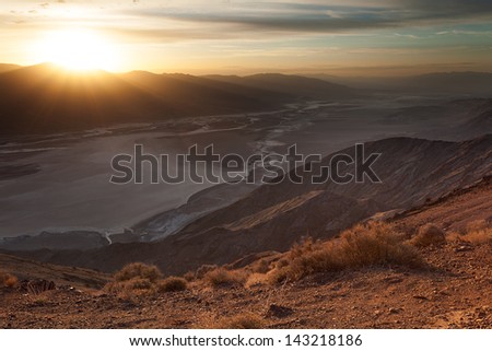The setting sun casts sunbeams over Badwater Basin salt flats in Death Valley, CA.  Taken from Dante\'s View.