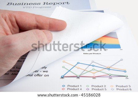 A male hand turns over a page whilst reviewing a sales report.
