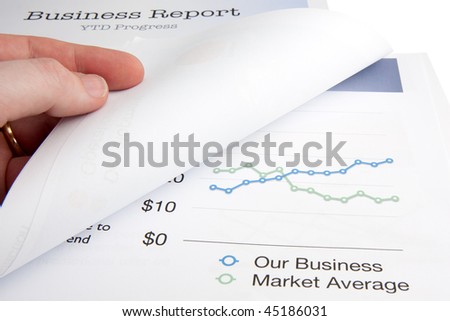 A male hand turns over a page whilst reviewing a business report.