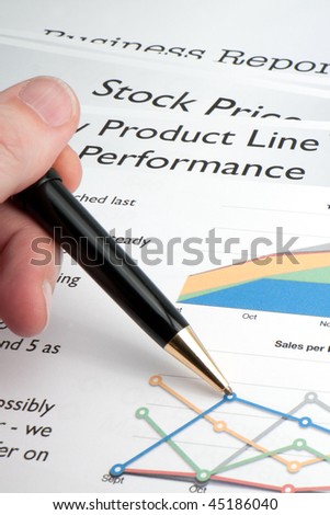 A male hand uses a pen to trace a sales chart for his business.