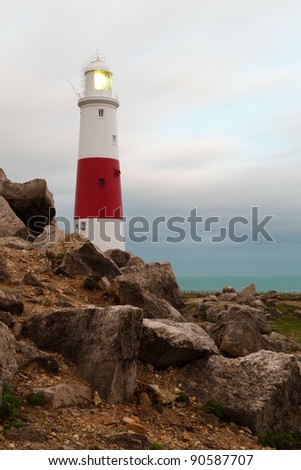 A closeup of some Portland stone with the Portland Bill Lighthouse in the background.  Taken after sunset so the lighthouse\'s light is on.