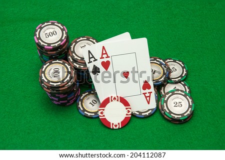 Cards showing pair of aces with chips on green background
