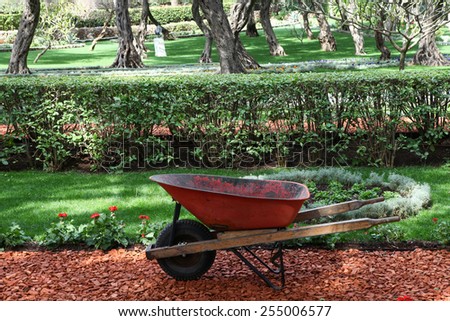 Garden work concept with wheelbarrow and beautiful garden.