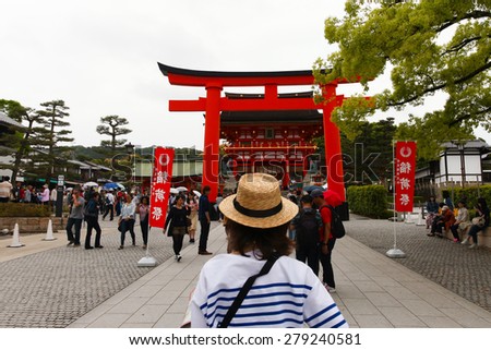Kyoto, Japan - May 4, 2015: : Japanese people and tourists enter Fushimi Inari Shrine in Kyoto. The road to the top of the mountain is reachable by a path lined with thousands of torii (orange gates).