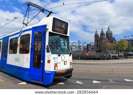 Amsterdam, The Netherlands - May 15, 2015: Tram (Local light rail transportation) heading to Amsterdam central station with the Church of Saint Nicolas in the background.