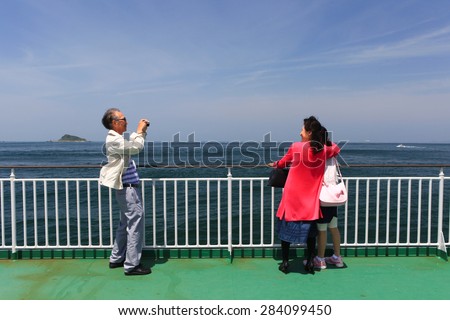 Toba, Japan - May 6, 2015: Japanese family taking photos onboard a passenger and cars ferry from Toba port to Irago port, during Japan\'s golden week holiday.