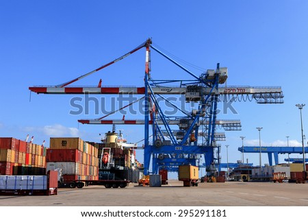 Haifa, Israel - July 10, 2015: Haifa\'s Port dock with container ship and Various brands and colors of shipping containers stacked in a holding platform waiting for loading.