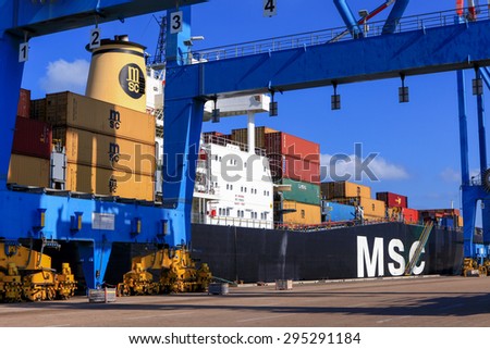 Haifa, Israel - July 10, 2015: Haifa\'s Port dock with container ship and Various brands and colors of shipping containers stacked in a holding platform waiting for loading.