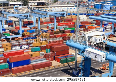 Haifa, Israel - July 10, 2015: Various brands and colors of shipping containers stacked in a holding platform waiting for loading.