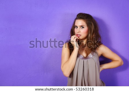 Shot of young and beautiful woman wearing beige dress and lilac accessories on lilac background. (Professional makeup and hair style)