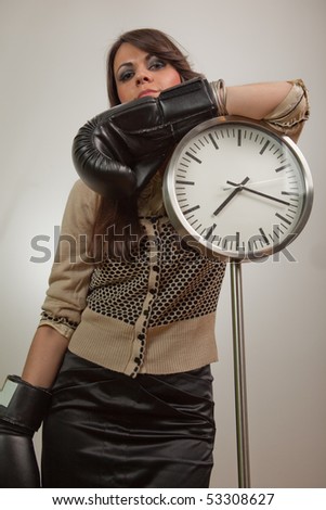 Young woman posing by the clock, wearing boxing gloves and looking self-confident