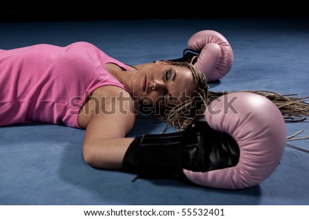 Blonde girl lying knocked out in a boxing ring
