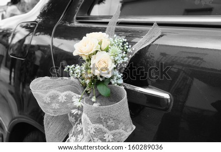 Door of black wedding car with flowers and white bow