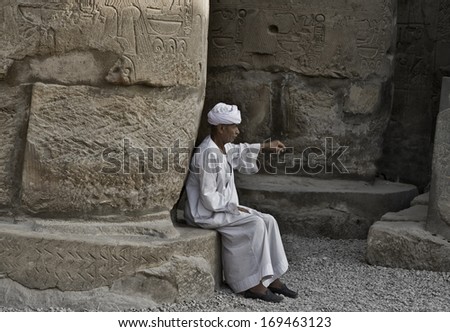 LUXOR, EGYPT - JULY 19, 2010: Old Egyptian beggar sitting on a base column of Luxor temple. On July 19, 2010 Luxor, Egypt