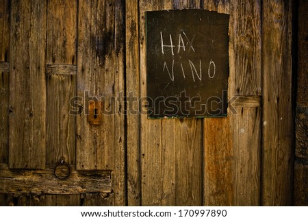 Advertisement written in black slate hanging of a wooden door that announces wine selling,  San Martin de Trevejo village, Caceres, Spain