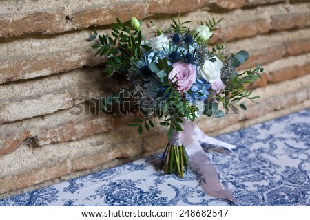 Wedding bouquet of bride. Bridal flowers bouquet in wedding day with blue, white, pink, and green flowers over brick wall