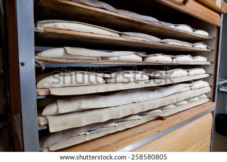 Raw pieces of bread in the fermentation wooden cabinet. Manufacturing process of spanish bread