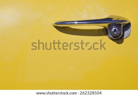 Chromed classic yellow car door handle. Detail of a luxury car