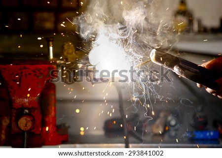 Stick welding worker in action with no protection gloves