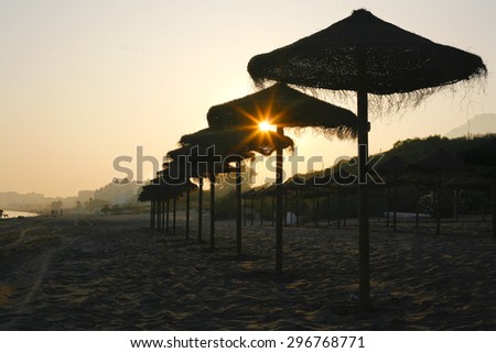 Rustic brown sun umbrellas made of natural fibers on a nice beach in Costa del Sol, Spain